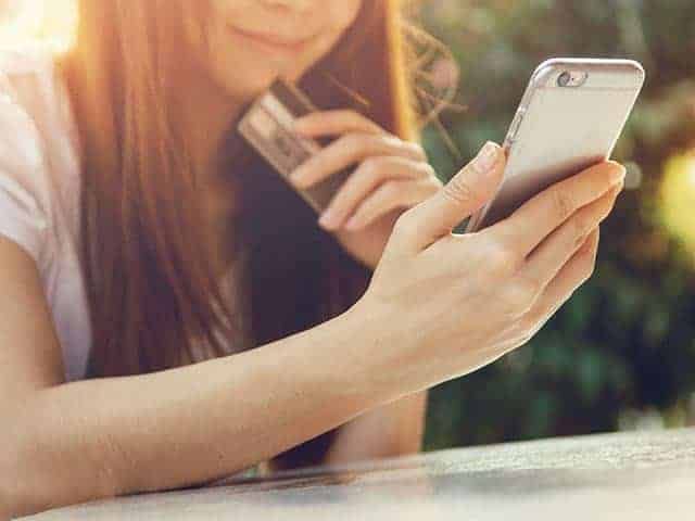 Close up hands holding credit card and using mobile smart phone outdoor