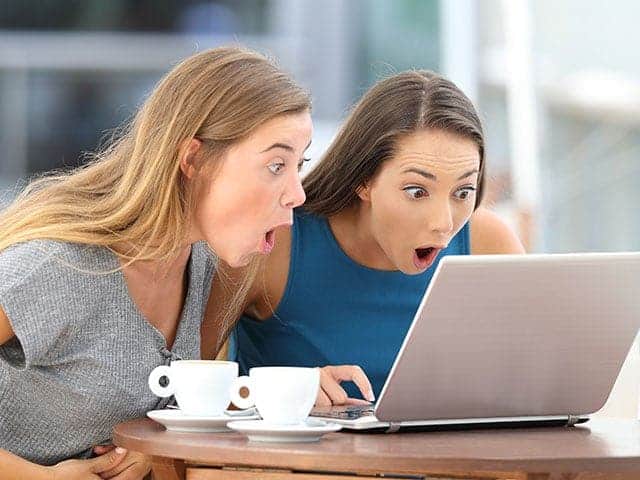 two women looking at a laptop screen in surprise
