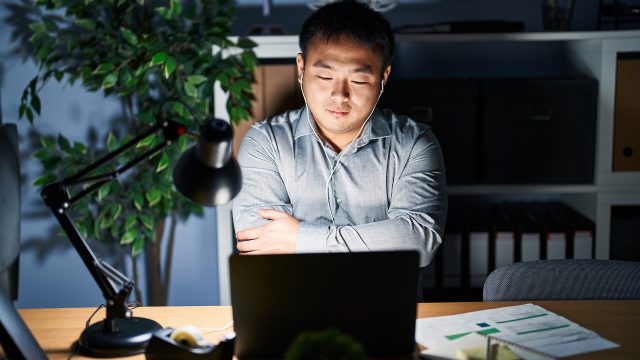 Young asian man at night thinking about the pros and cons of paying a web designer for his website project