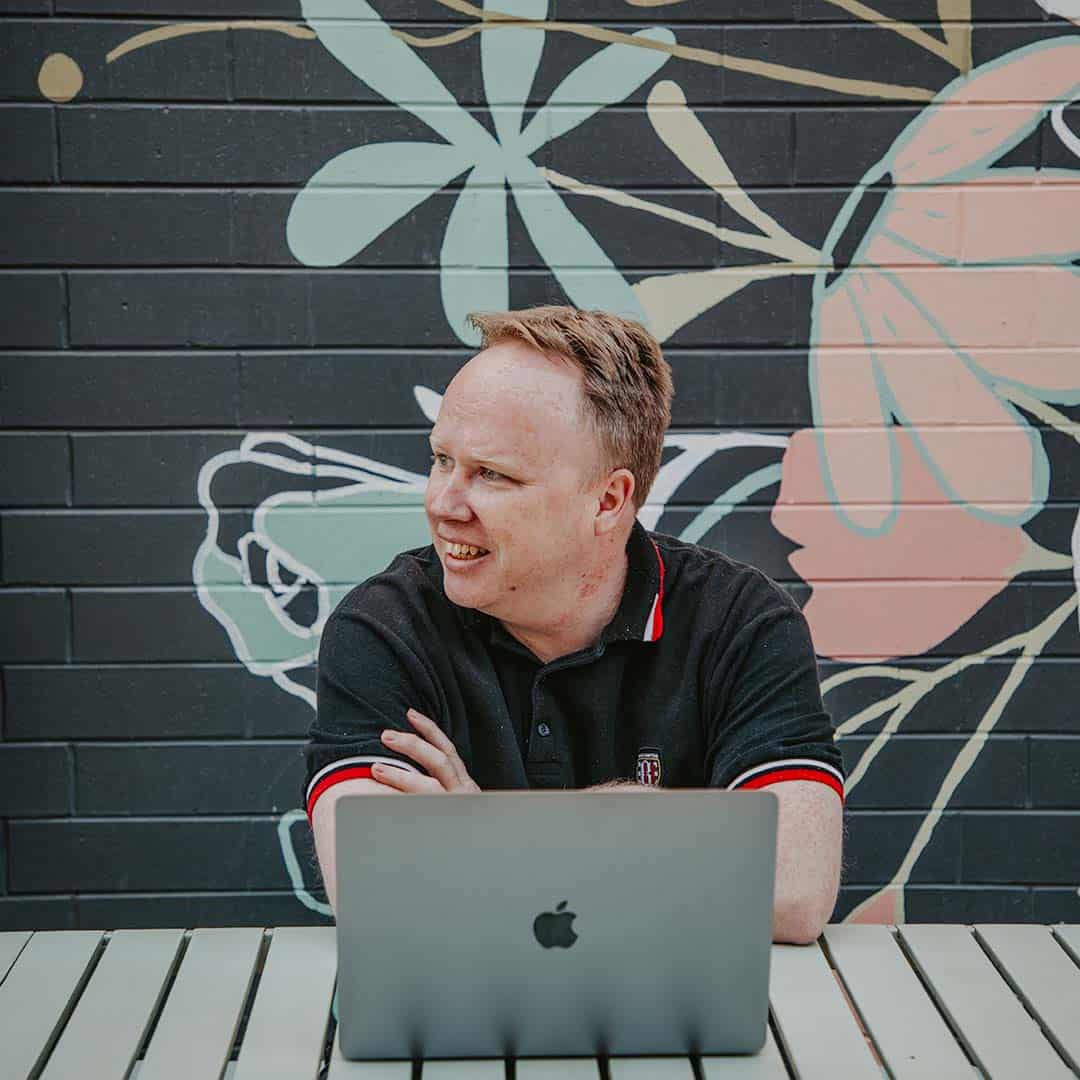 Jarrod Partridge seated looking away from his MacBook