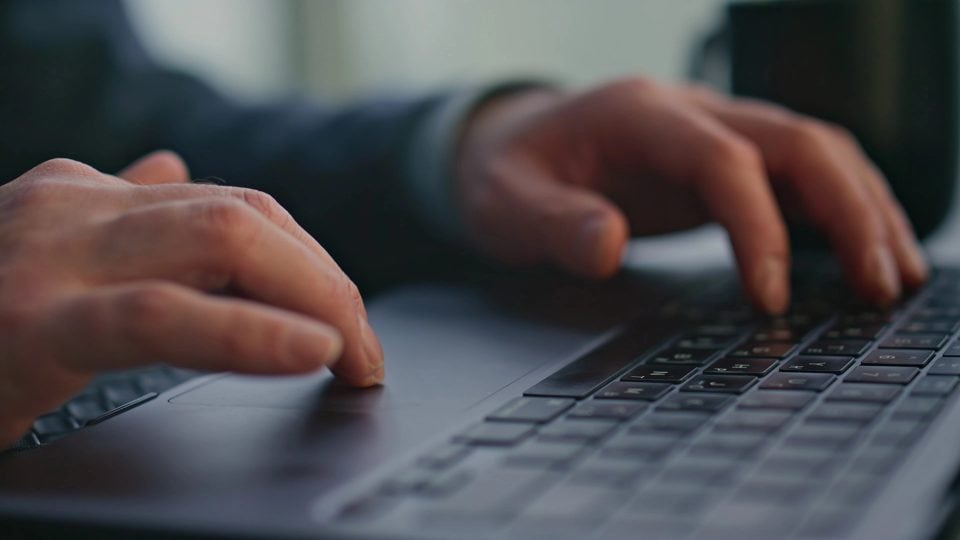 Close-up of hands typing on laptop keyboard
