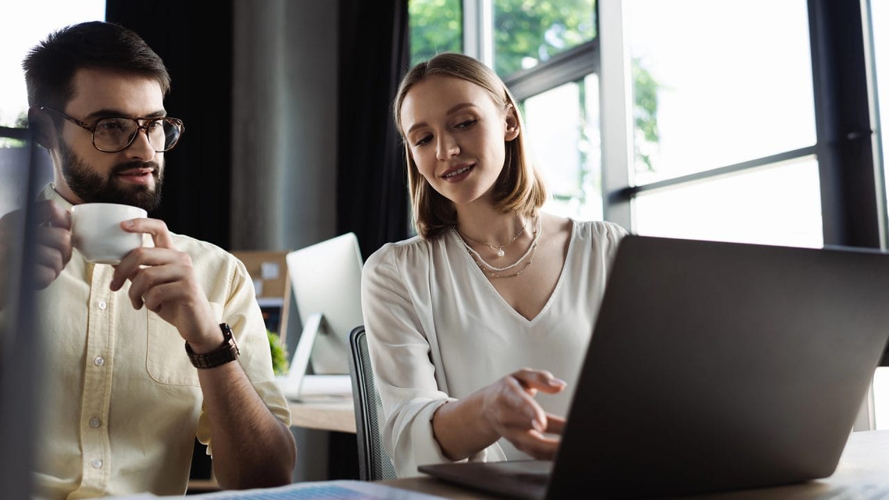 Two professionals collaborating with laptop in modern office
