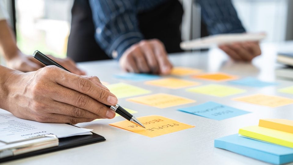 Two creatives meeting and planning use post it notes sticky note on desk to plan a web design project.