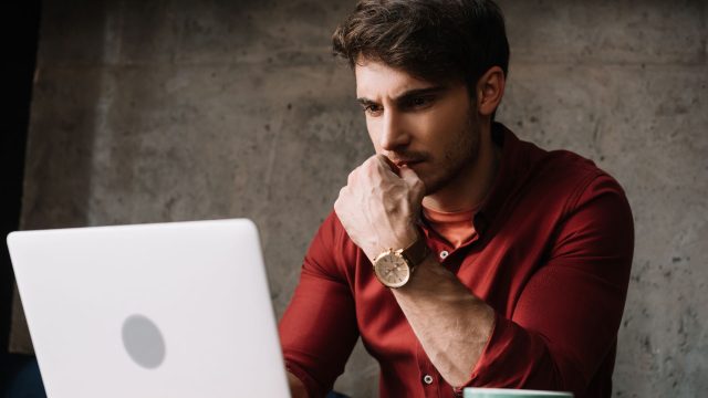 man working on his laptop and thinking deeply