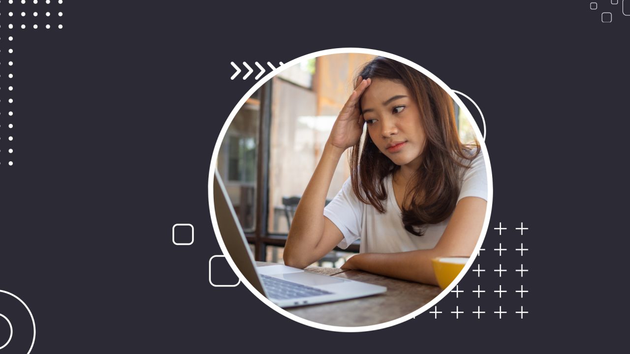 woman looking confused while working on her laptop in a cafe