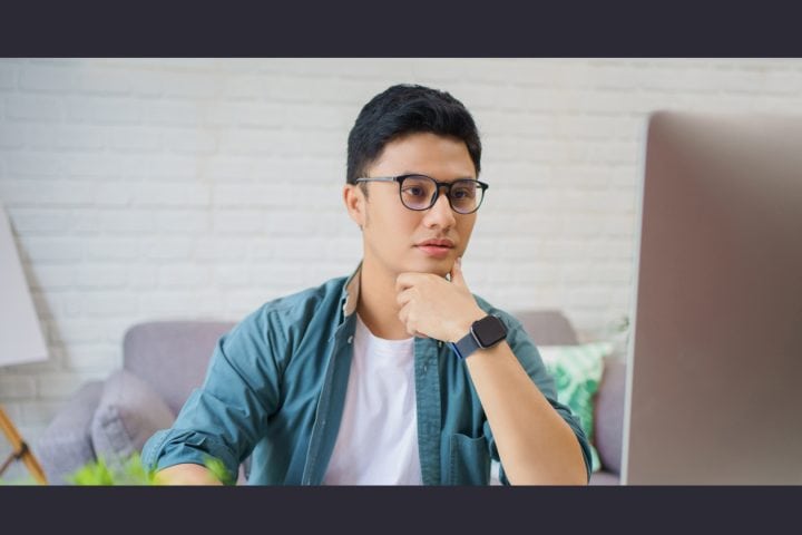 Young man with glasses using laptop in modern room