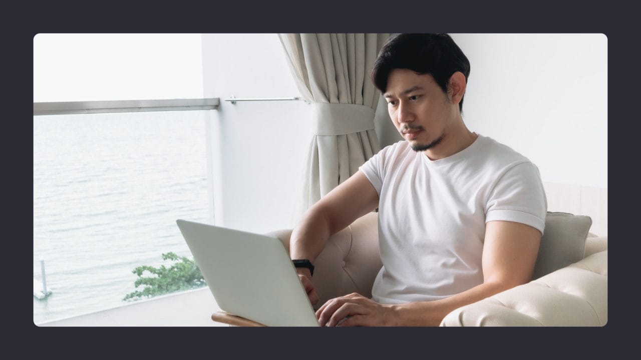 Man using laptop by seaside window