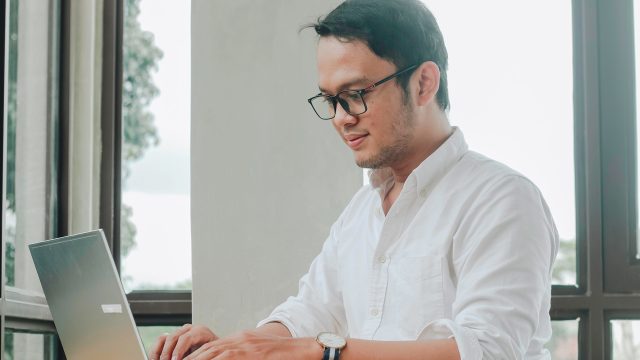Man using laptop by window in modern office