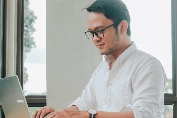 Man using laptop by window in modern office