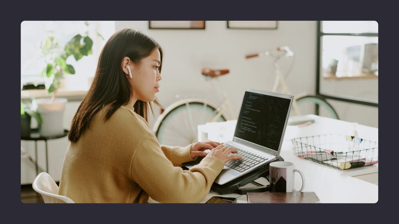 Woman coding on laptop in sunny home office