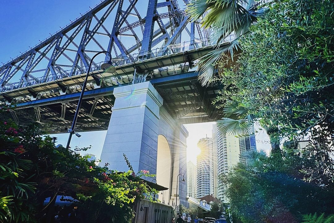 Brisbane Story Bridge framed by lush greenery and sunlight