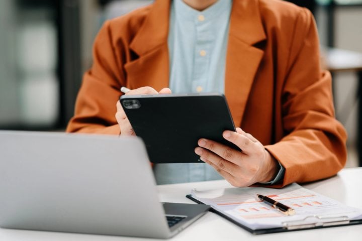 Businessman using tablet and laptop at modern office desk