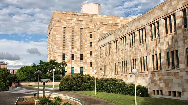 University sandstone building with garden and walkway.