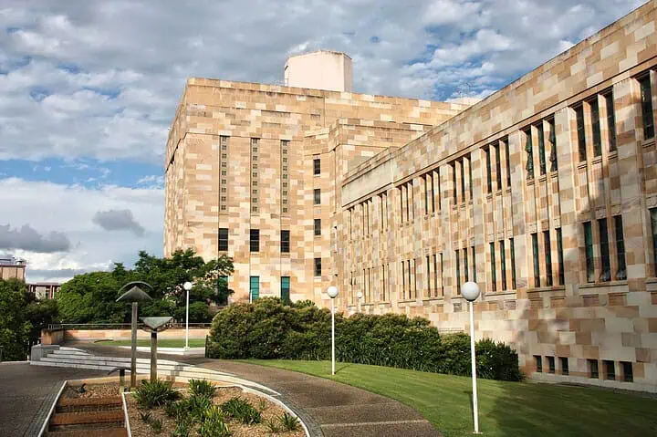 University sandstone building with garden and walkway.