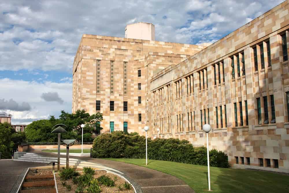 University sandstone building with garden and walkway.