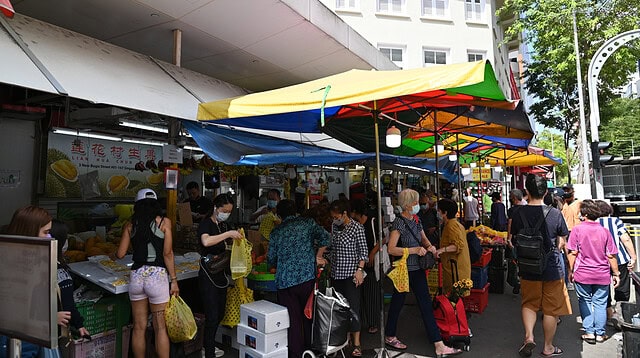 Busy market with colourful umbrellas and shoppers.