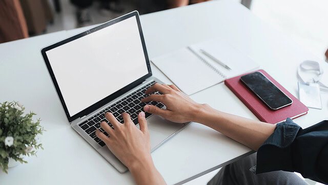 Person typing on laptop at white desk