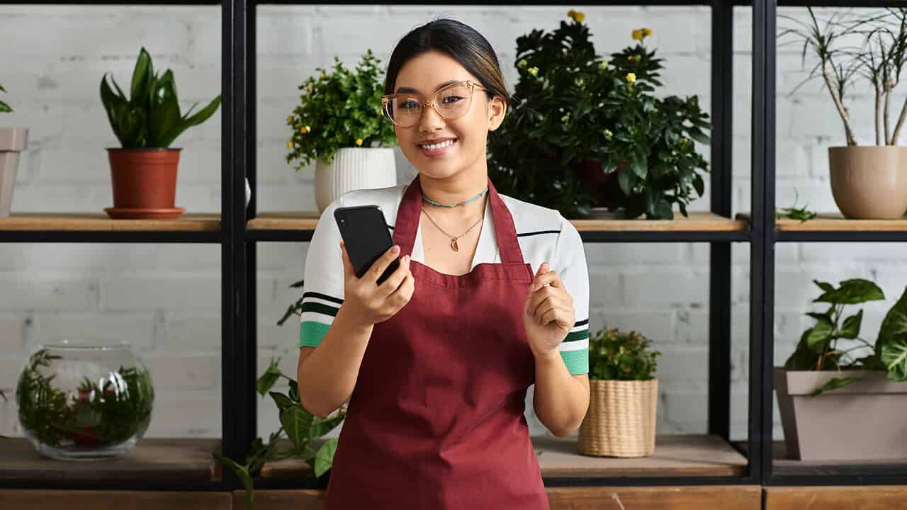 Florist on phone, surrounded by plants.