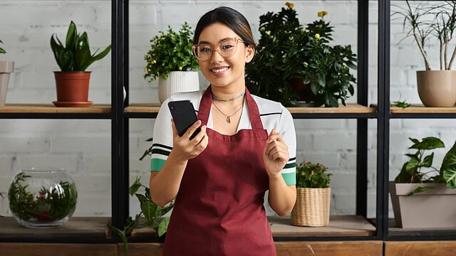 Florist on phone, surrounded by plants.