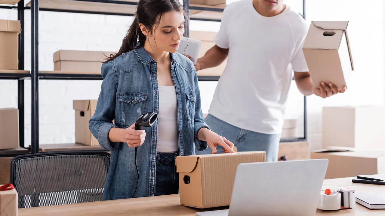 Two people scanning and packing small boxes for online customer delivery