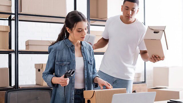 Two people scanning and packing small boxes for online customer delivery